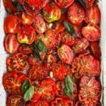 Sliced tomatoes and herbs in a baking sheet.