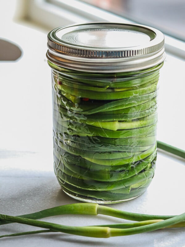 Pickled garlic scapes in a mason jar.