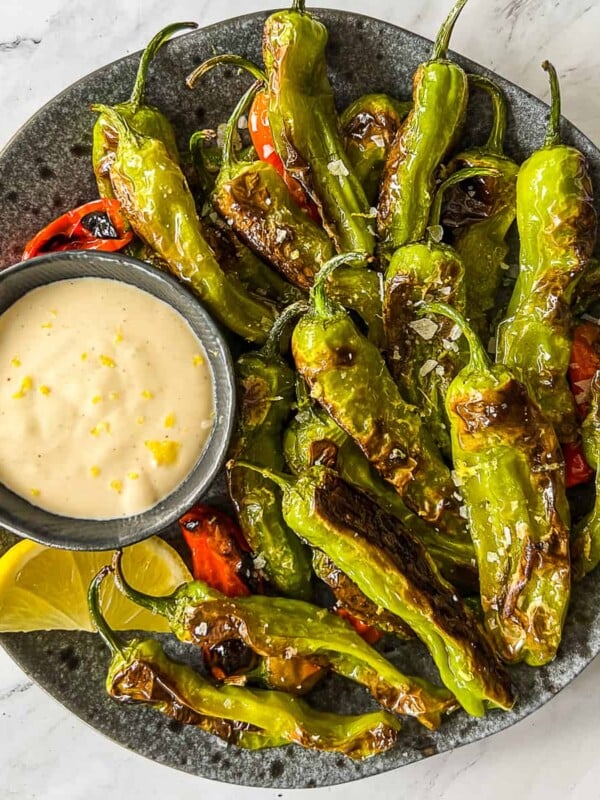 shishito peppers with dipping sauce on a plate.