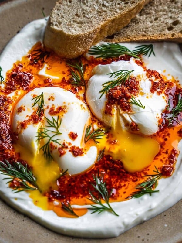 Poached eggs with chili oil and dill on a plate.