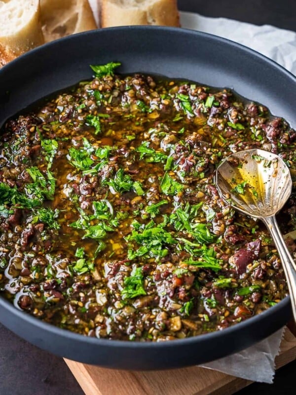 Bread dipping oil in a bowl with a spoon.