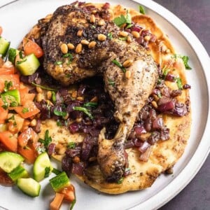 Sumac chicken thigh on a bed of onions and naan.