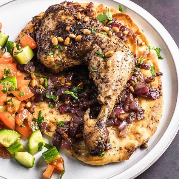 Sumac chicken thigh on a bed of onions and naan.