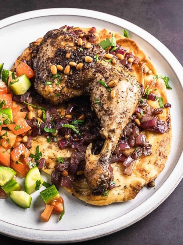 Sumac chicken thigh on a bed of onions and naan.