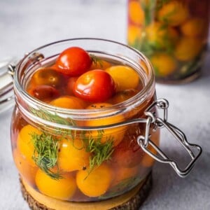 Cherry tomatoes with dill and garlic in a pickling jar.
