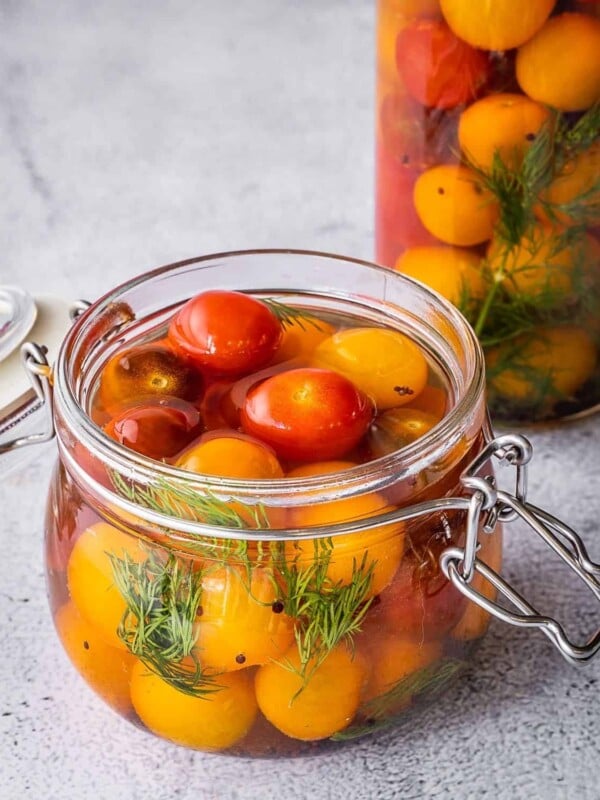 Cherry tomatoes with dill and garlic in a pickling jar.