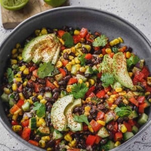 Fiesta salad with corn, beans, peppers and cilantro in a bowl with avocado.