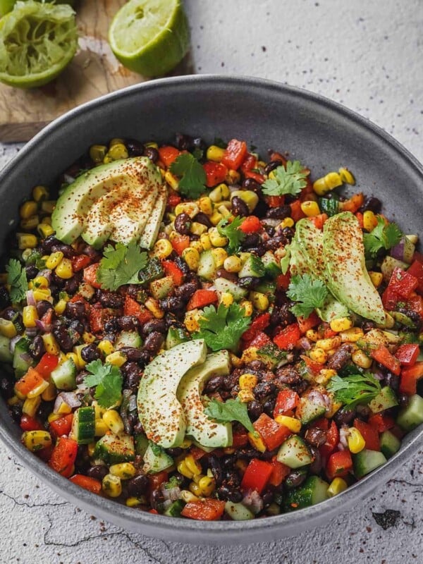 Fiesta salad with corn, beans, peppers and cilantro in a bowl with avocado.