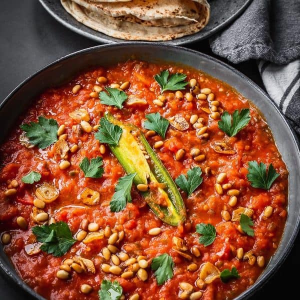 A plate with levantine fried tomatoes garnished with parsley.