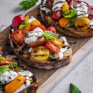 Burrata bruschetta toasts with cherry tomatoes and cheese.