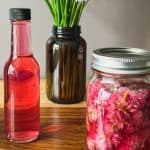 Mason jar and bottle with purple chive vinegar.