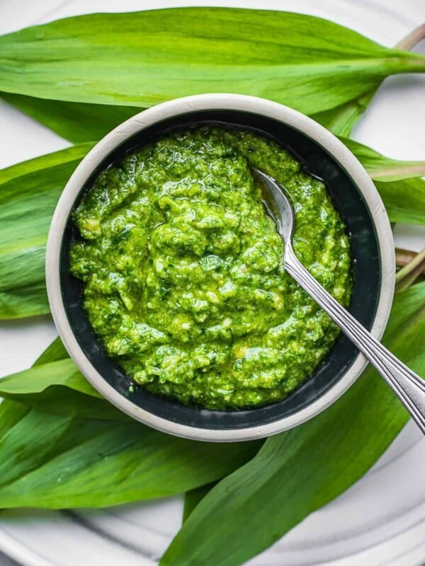 Wild leek pesto in a bowl on top of ramp leaves.
