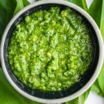 Wild leek pesto in a bowl on top of ramp leaves.