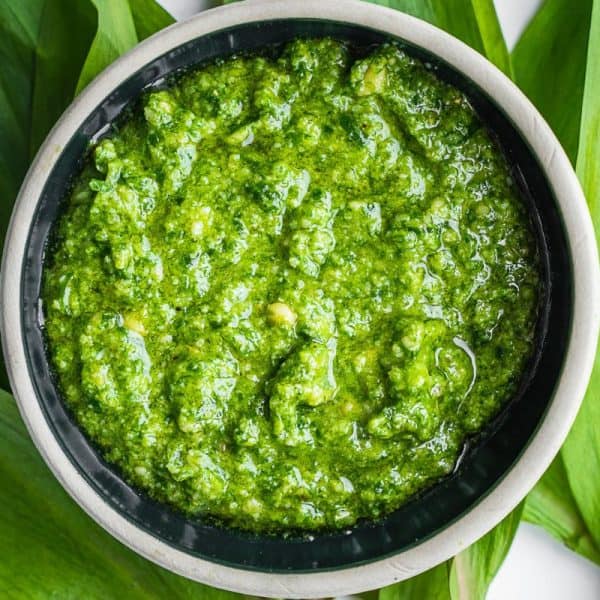Wild leek pesto in a bowl on top of ramp leaves.