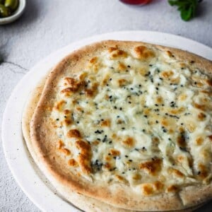 Cheesy flatbreads on a plate with olives and mint tea on the side.