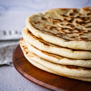 Stack of flatbread on a wooden board.