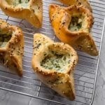 Cheese and herb fatayer pastries with sesame seeds on a cooling rack.