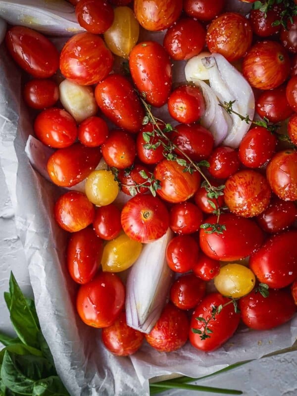 Cherry tomatoes with onions, garlic and thyme in a baking tray.