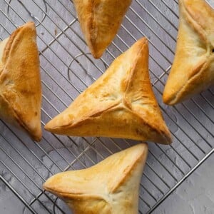 Triangular spinach fatayer pastries on a cooling rack.