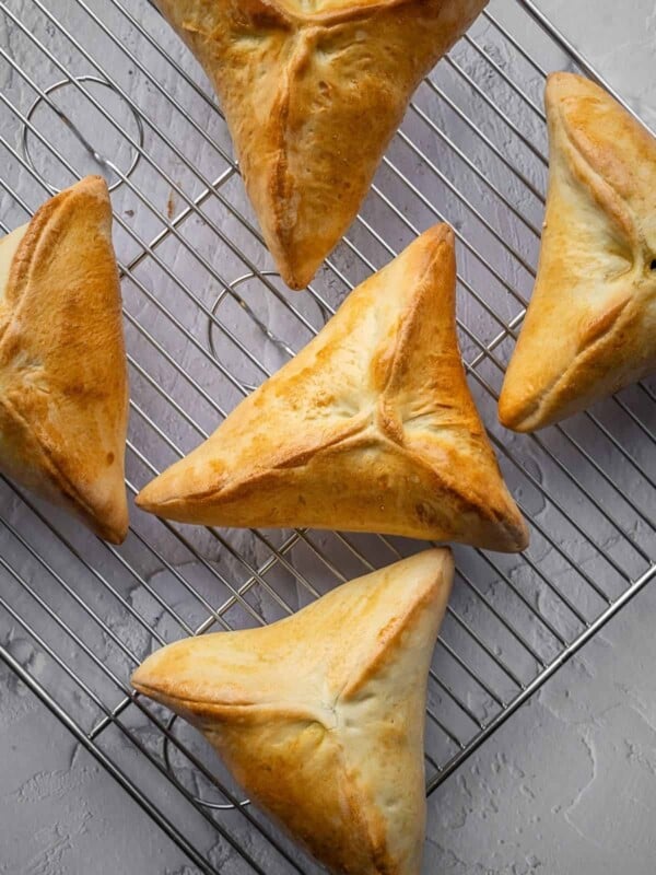 Triangular spinach fatayer pastries on a cooling rack.