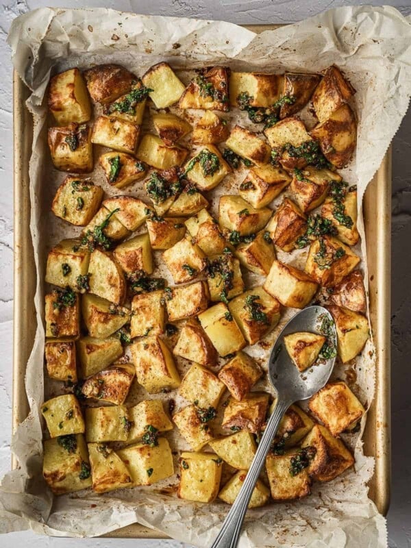 Sheet ban with cooked cubed potatoes drizzled with the garlic herb sauce.
