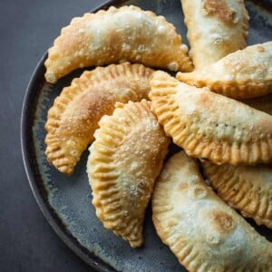 Fried half-moon pastries on a plate.