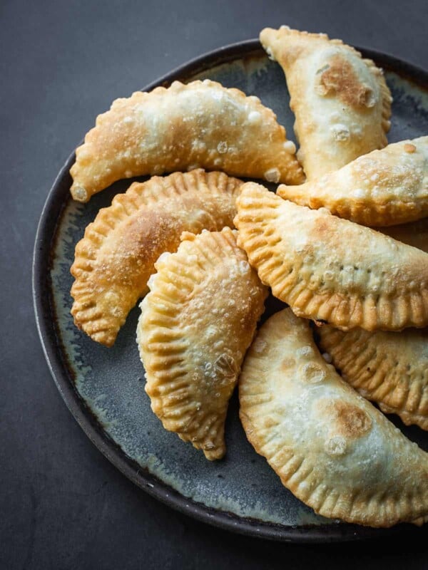 Fried half-moon pastries on a plate.