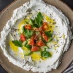 A plate of labneh topped with tomatoes and cucumbers.