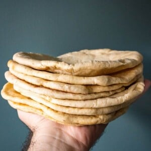 A stack of pita bread held in a hand.