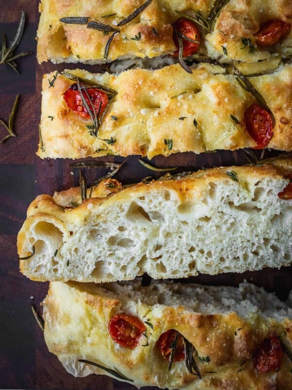 Slices of tomato focaccia on a wooden cutting board showing the crumb cross section.