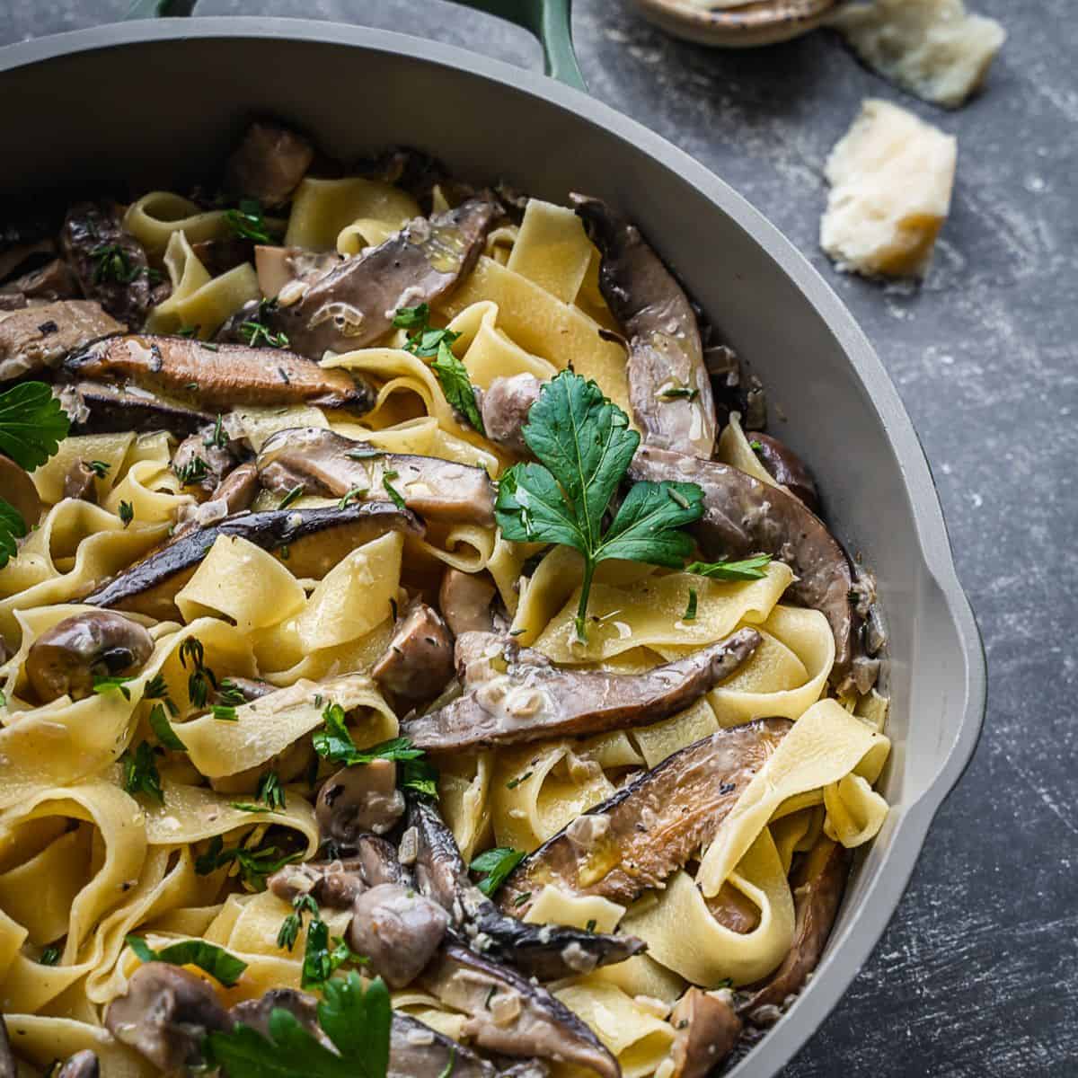 A pan with mushrooms, parsley and pasta.