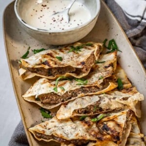 Arayes tray with stuffed pita quarters and a tahini dipping sauce.