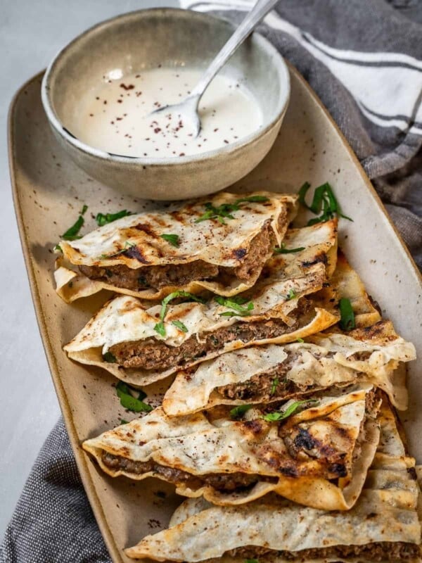 Arayes tray with stuffed pita quarters and a tahini dipping sauce.