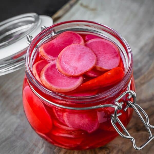 A jar with fermented pink radish slices.