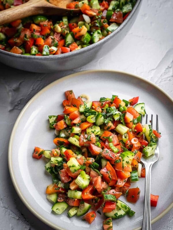 Chopped salad on a plate next to the serving bowl.