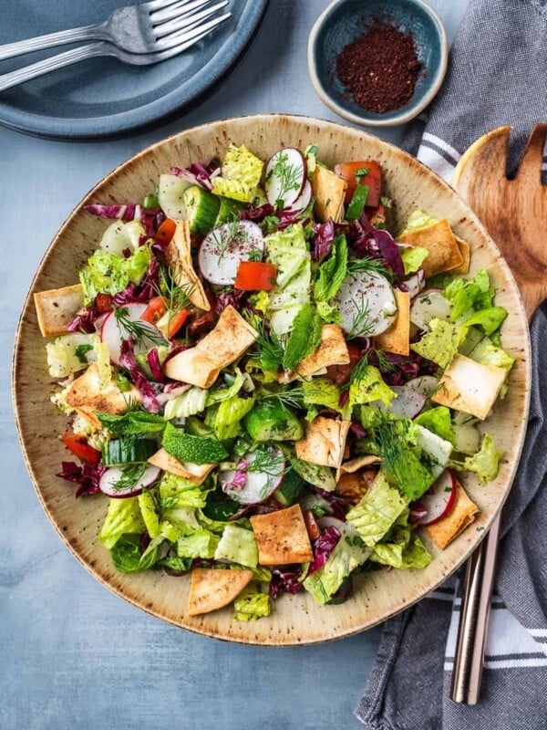Chopped salad with lettuce, cucumbers and tomatoes in a bowl with crispy pita chips.