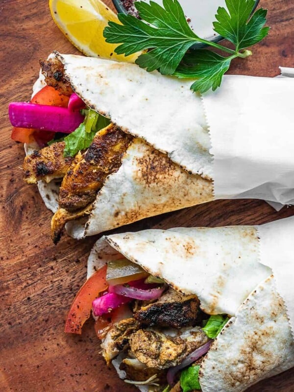 Chicken shawarma pita wraps on a board.