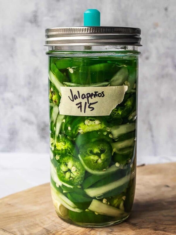 A mason jar with jalapeno slices fermenting in brine.