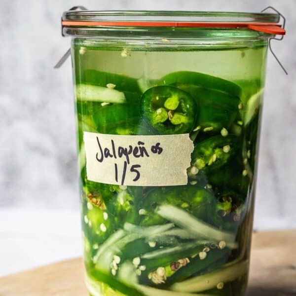 A Weck glass jar with sliced jalapenos and onions.