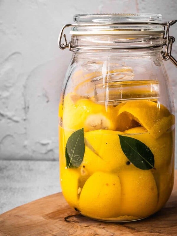 A jar of fermented lemons on a cutting board.
