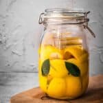 A jar of fermented lemons on a cutting board.