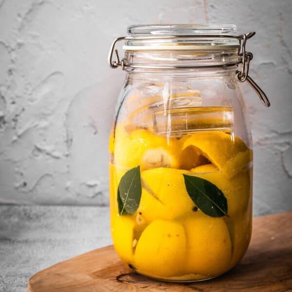 A jar of fermented lemons on a cutting board.