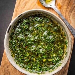 Mint chimichurri sauce in a bowl on a cutting board.