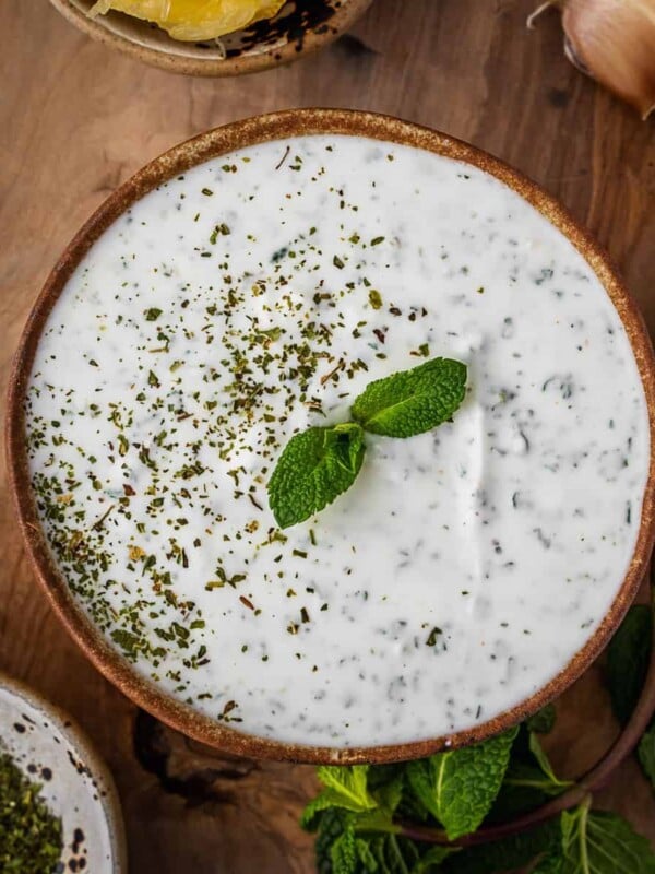 Mint yogurt sauce in a bowl with mint garnish.