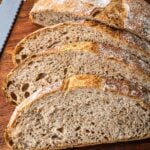 Sliced no knead whole wheat bread on a wooden cutting board.