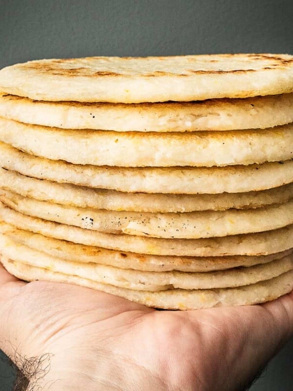 A hand holding a stack of from scratch Colombian arepas.