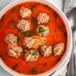 Bowl of kofta meatball soup with noodles in a tomato broth.