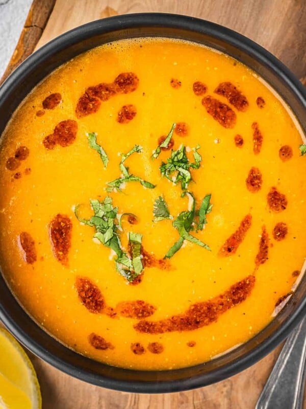 Bowl of red lentil soup garnished with chili oil and cilantro.