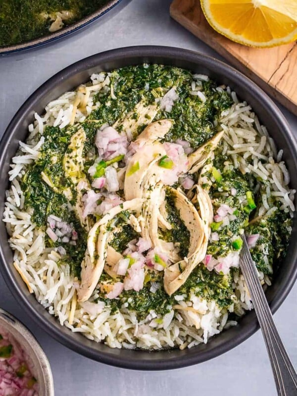 A bowl of molokhia and rice with a side of chopped onions and lemons.