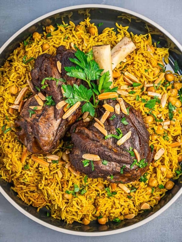 A large bowl of rice and chickpeas topped with tender lamb shanks.